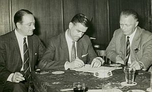 Coen Dillen, (ex-P.S.V.) tekent een contract bij Helmondia. Links voorzitter A. M. Melters en rechts ere-voorzitter W.F.B. Claus, juli 1961. Foto: RHC Eindhoven, nr. 111792.