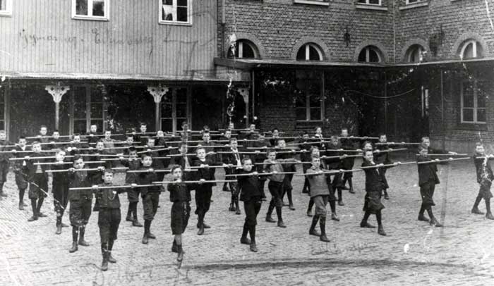 Leerlingen van Eikenburg krijgen gymnastiekoefeningen op de binnenplaats, 1909-1911. Een van deze jongens is W. van Woerkom uit Oerle. (Foto: collectie Regionaal Historisch Centrum Eindhoven 191)