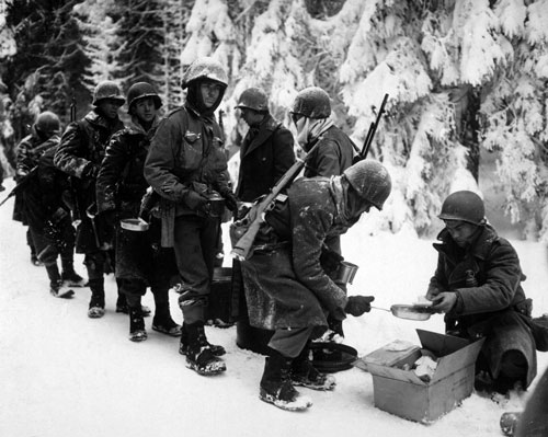 Het Ardennenoffensief. Amerikaanse troepen krijgen een maaltijd op weg naar La Roche-en-Ardenne op 13 januari 1945. (Bron: Wikimedia Commons. Publiek Domein)