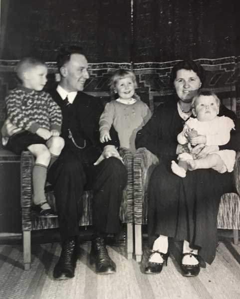 Het gezin De Boer in gelukkige tijden in de Elzenstraat: 1935, kort na de geboorte van Lenie (zusje Riek blij en midden tussen vader en moeder op de achtergrond)