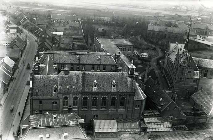 Het oude klooster van de fraters aan de Begijnenstraat in Oss, gezien vanaf de Grote Kerk, 1932. In 1961 betrokken zij een nieuw klooster in dezelfde straat. (Fotopersbureau Het Zuiden, collectie Stadsarchief Oss BCO010719)