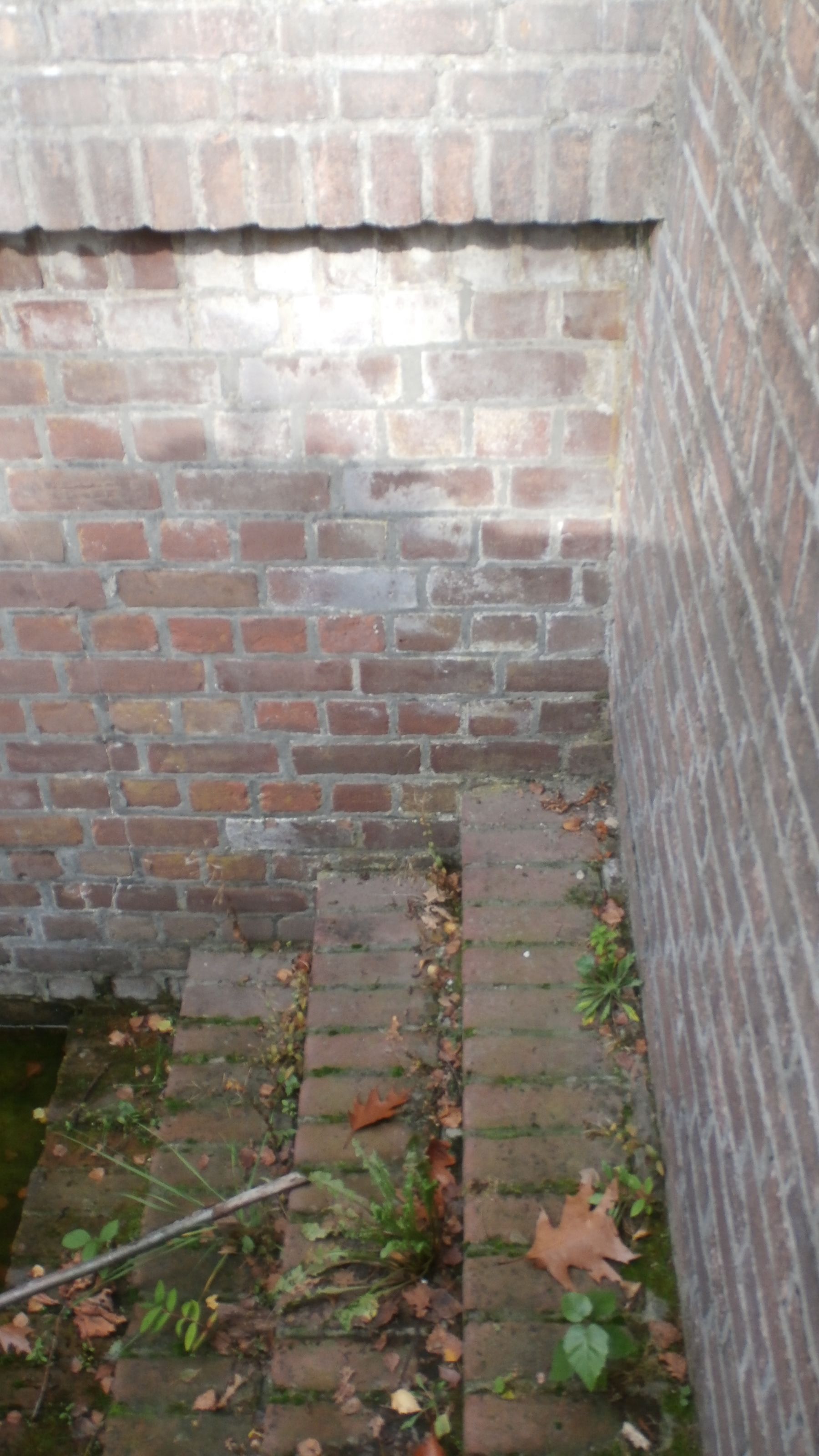 Foto 4: de (later gereconstrueerde onderste treden van de) toegangstrap bestaan uit 5 cm. dikke stenen net als de (nieuwe) muur naar de bovenrand van het monument (rechter rand van de foto).