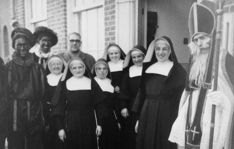 De zusters kregen bezoek van Sinterklaas en Zwarte Piet in de jaren '50. Op de achtergrond meester Mouwen.